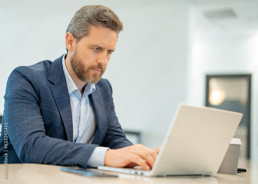Man with laptop at office. Business man in suit in office work on laptop computer. Office worker using laptop. Business man work on laptop. Businessman have online work in modern office interior. Man with laptop at office. Business man in suit in office work on laptop computer. Office worker using laptop. Business man work on laptop. Businessman have online work in modern office interior.