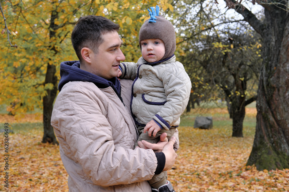 Dad and son spend time together in the autumn park. Father holding his son in his arms Dad and son spend time together in the autumn park. Father holding his son in his arms