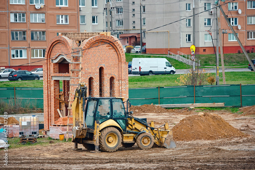 Wheel loader with backhoe on cunstruction site, building new church. Wheel loader or bulldozer working on construction site. Construction site, earthworks with heavy duty machine. photo