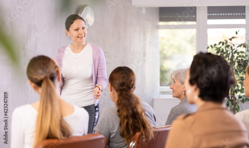 Adult woman lecturer in casual clothes leads discussion with audience in office