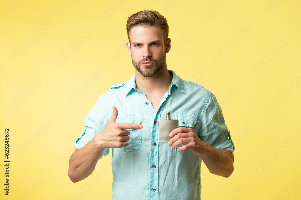 photo of man hold cologne, point finger. man hold cologne. man hold cologne isolated on yellow. photo of man hold cologne, point finger. man hold cologne. man hold cologne isolated on yellow.