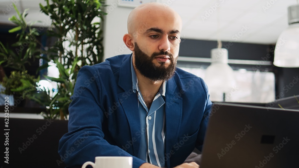 Businessman solving startup problems with laptop and archived documents, looking at annual statistics report to find issue. Young analyst reviewing papers, executive strategy plan.