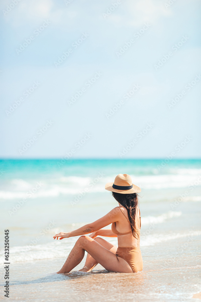 Young happy woman on the beach enjoy her summer vacation. Woman relax on the seashore Young happy woman on the beach enjoy her summer vacation. Woman relax on the seashore