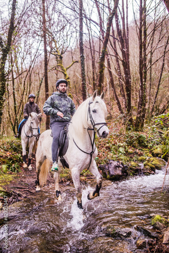 Horse riding, Way of st James in Fragas do Eume, Galicia. Hispanic pilgrim mid couple equitation
