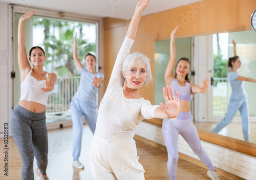 Group of active women practicing energetic dance in a modern dance studio