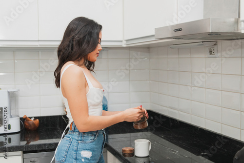 Tall girl preparing a morning coffee in the kitchen of her home.