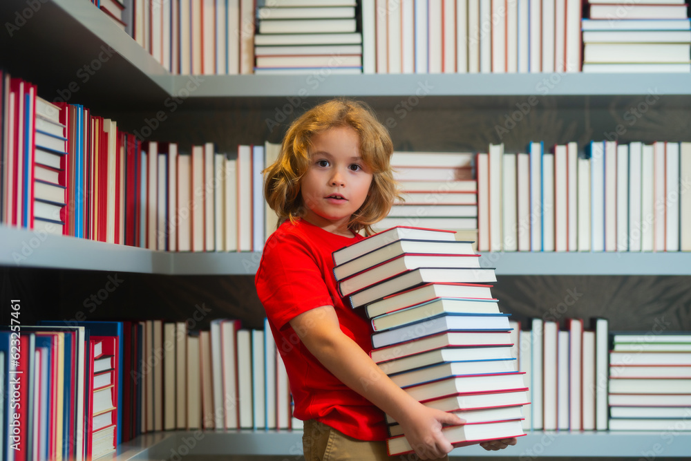 School and education concept. School boy doing homework on desk in school library. Pupil child studying homework literature near pile of books. School and education concept. School boy doing homework on desk in school library. Pupil child studying homework literature near pile of books.