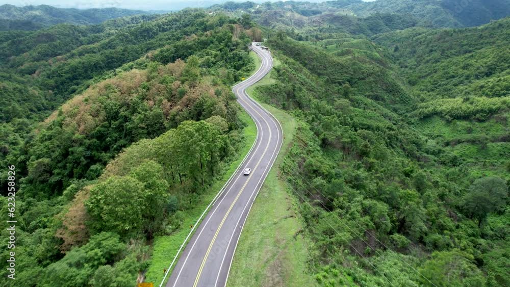 Aerial view of car driving on country road in forest. Cinematic drone shot flying over country road with curved in the mountain. Aerial view of car driving on country road in forest. Cinematic drone shot flying over country road with curved in the mountain.