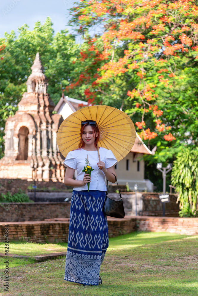 Asian beautiful wearing Thai traditional dress holding umbrella in ancient temple