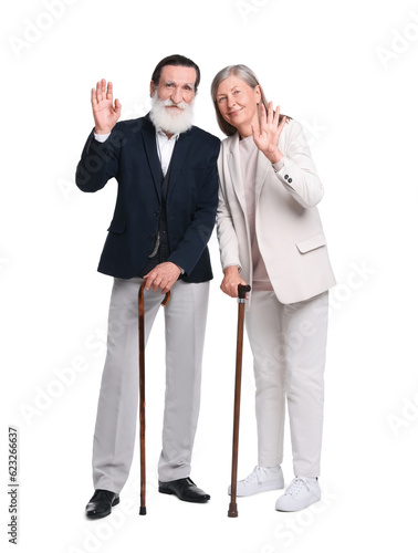Senior man and woman with walking canes waving on white background