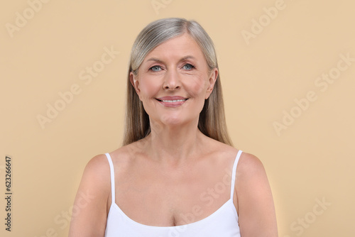Portrait of beautiful senior woman on beige background