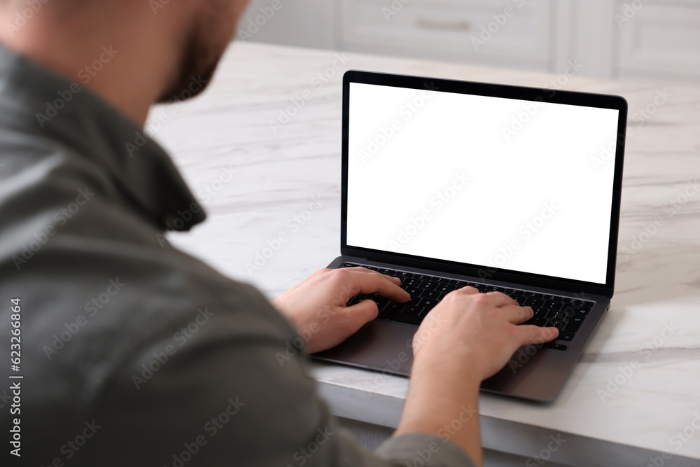 Man working on laptop at white marble table indoors, closeup