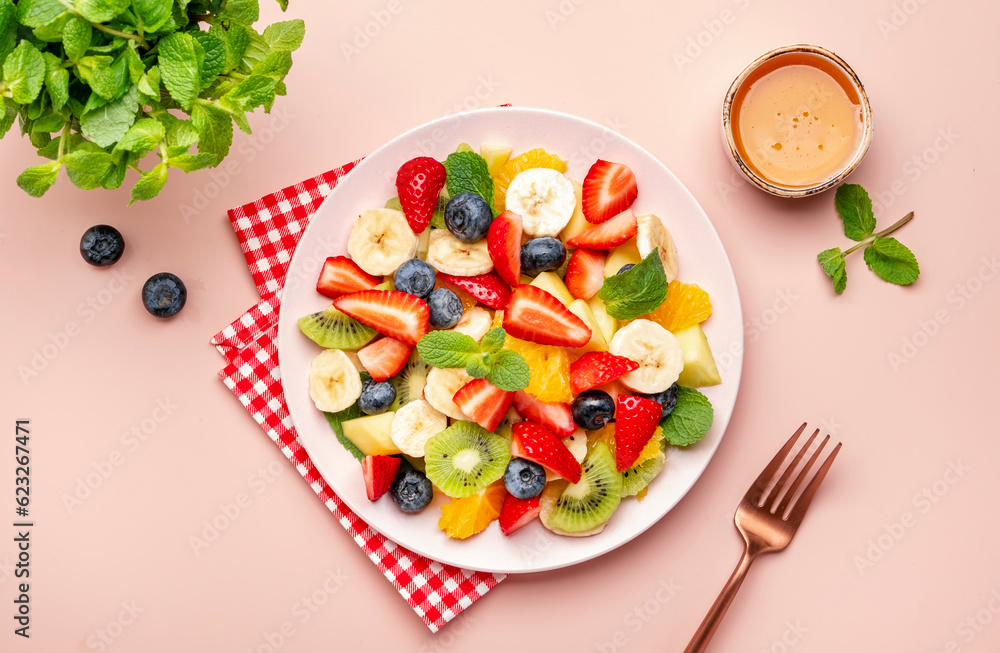 Summer fruit and berry salad with fresh strawberries, blueberries, banana, kiwi, orange and mint, pink background, top view Summer fruit and berry salad with fresh strawberries, blueberries, banana, kiwi, orange and mint, pink background, top view