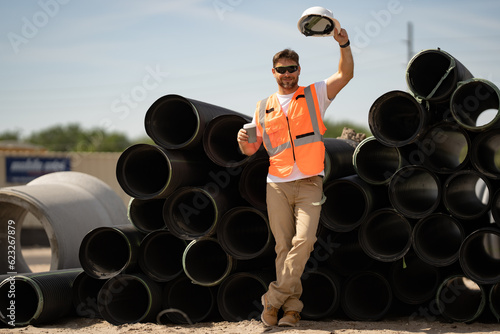 Slika na platnu Worker in helmet on break near sewerage pipes