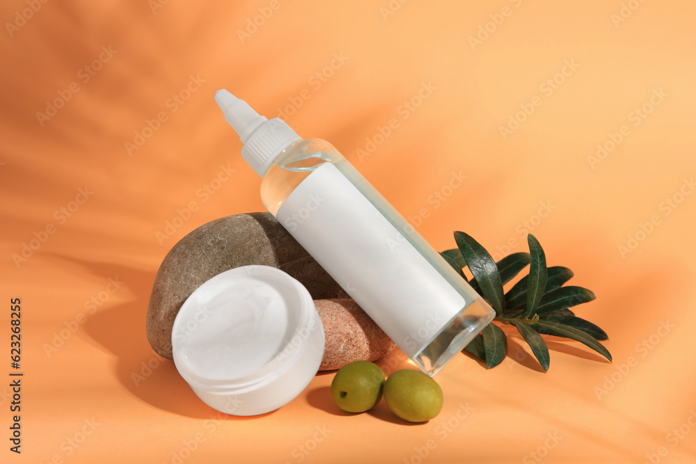 Cosmetic products and olives on orange background Cosmetic products and olives on orange background