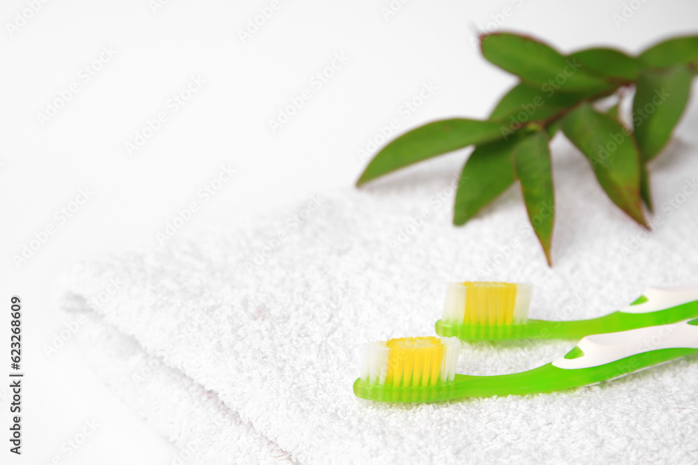 Light green toothbrushes on white terry towel Light green toothbrushes on white terry towel