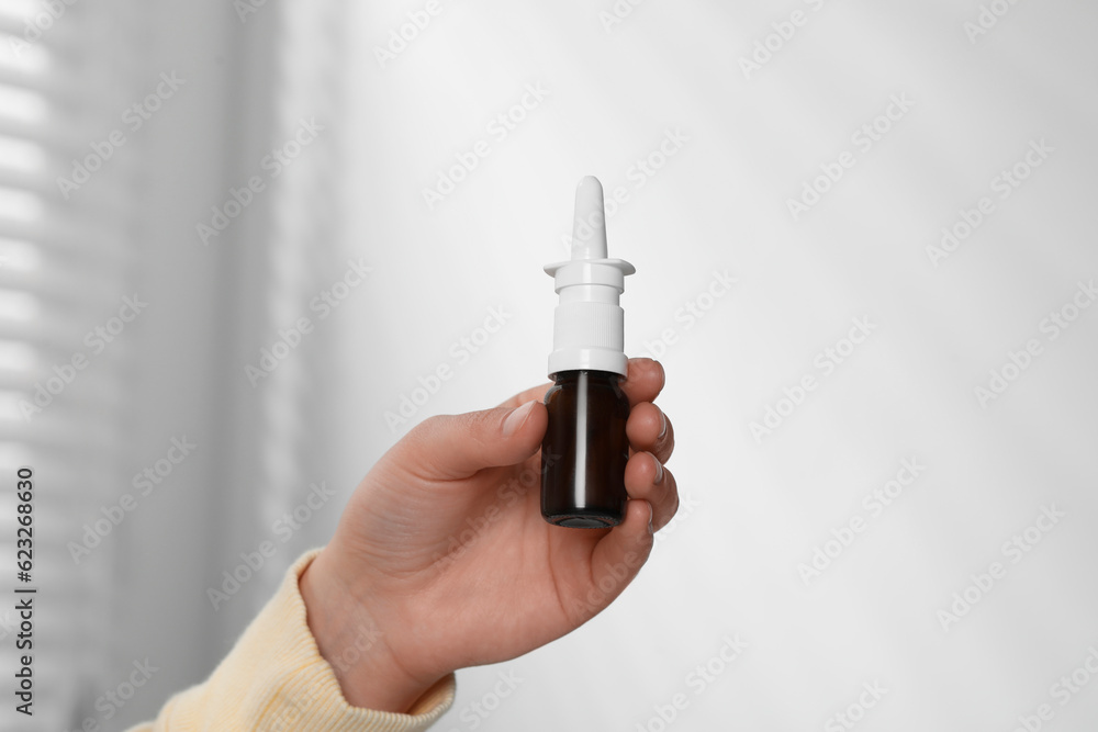 Woman holding nasal spray indoors, closeup view Woman holding nasal spray indoors, closeup view