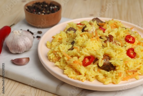 Delicious pilaf with meat and ingredients on wooden table, closeup