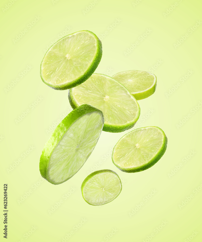 Fresh lime slices falling on light green background Fresh lime slices falling on light green background