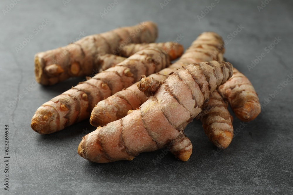 Many raw turmeric roots on grey table, closeup Many raw turmeric roots on grey table, closeup