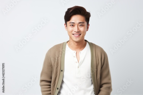 Portrait of a happy young asian man standing over white background