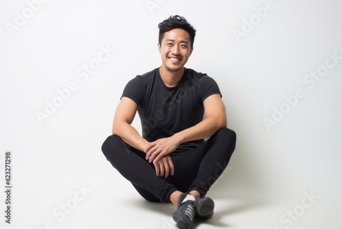 Portrait of a smiling asian man sitting on the floor.