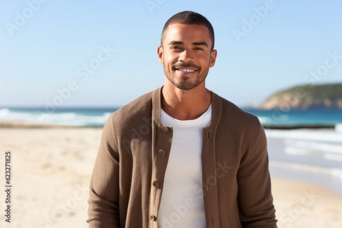 Portrait of a handsome young man smiling at the beach on an autumn day