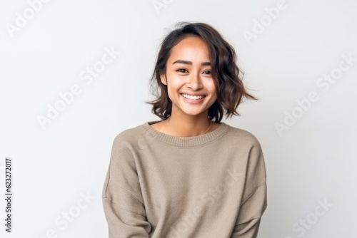 Smiling young Asian woman in sweater standing and looking at camera.