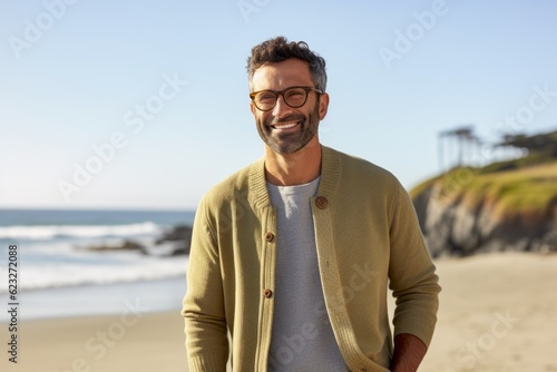Lifestyle portrait photography of a satisfied Brazilian man in his 40s wearing a chic cardigan against a beach background 