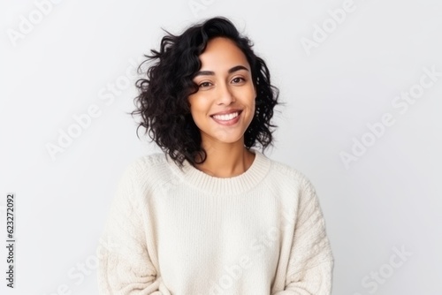 Portrait of smiling young woman in sweater looking at camera over white background