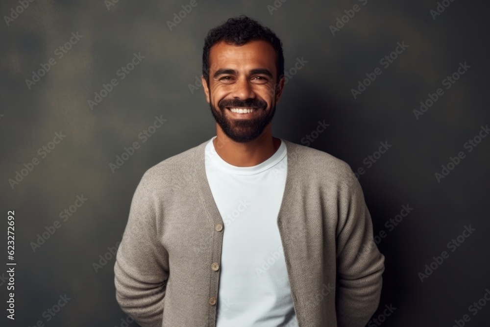 Handsome young African man smiling and looking at camera while standing against grey background