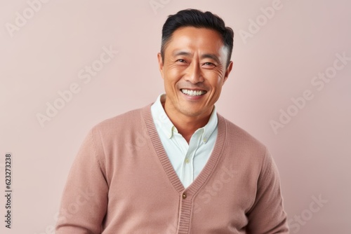 Portrait of a happy asian man smiling at camera isolated on a pink background