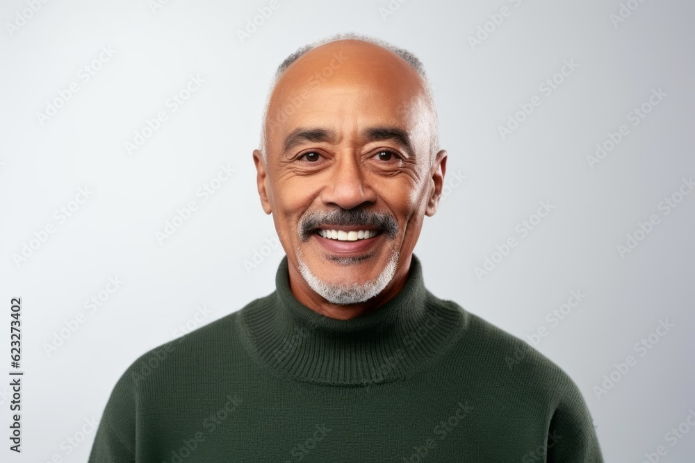 Portrait of a senior Indian man smiling at the camera against grey background Portrait of a senior Indian man smiling at the camera against grey background