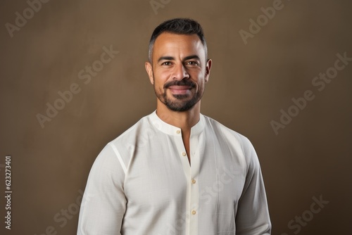 Portrait of handsome bearded Indian man in white shirt looking at camera