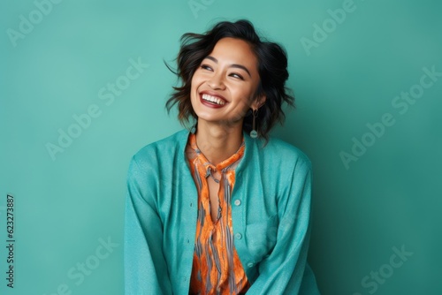 Portrait of a smiling young asian woman looking away isolated over green background