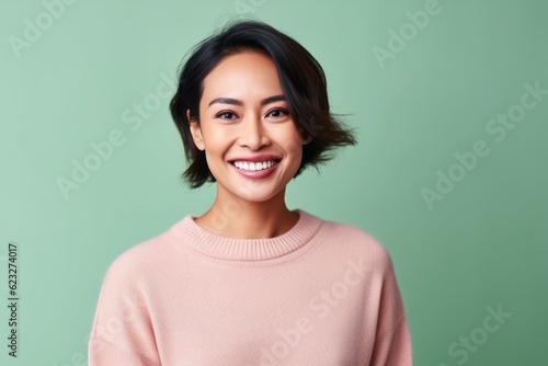 Portrait of a beautiful young asian woman smiling and looking at camera isolated over green background