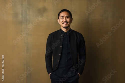 Portrait of a young asian man standing in front of a wall
