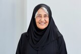 Medium shot portrait photography of a pleased Saudi Arabian woman in her 90s wearing a sleek suit against a white background 