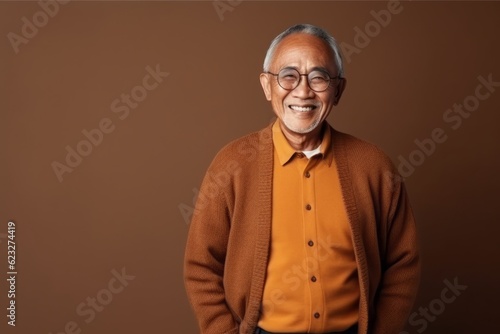 Medium shot portrait photography of a satisfied Indonesian man in his 70s wearing a chic cardigan against an abstract background  © Eber Braun