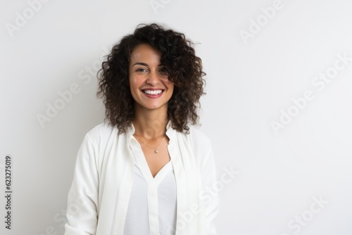 Portrait of smiling young woman with curly hair standing against white background