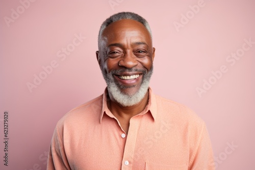Portrait of a senior Indian man smiling at camera against pink background