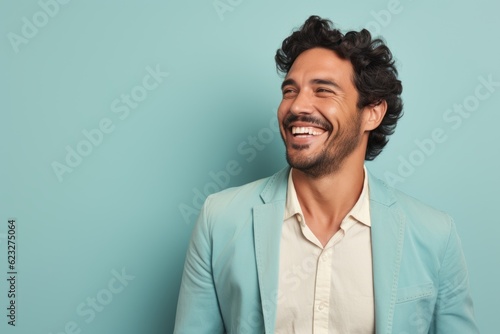 Handsome young man laughing and looking at camera against blue background