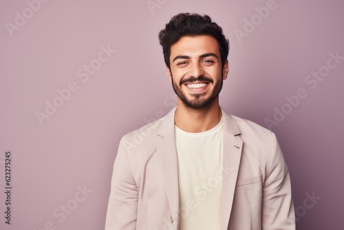 Handsome young man looking at camera and smiling while standing against purple background