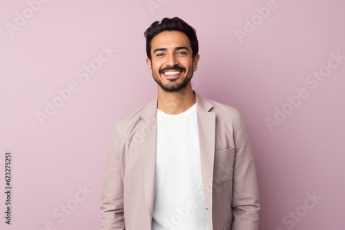 Portrait of a young indian man on a pink background.