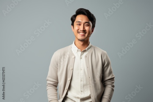 Lifestyle portrait photography of a satisfied Indonesian man in his 20s wearing a chic cardigan against a minimalist or empty room background 