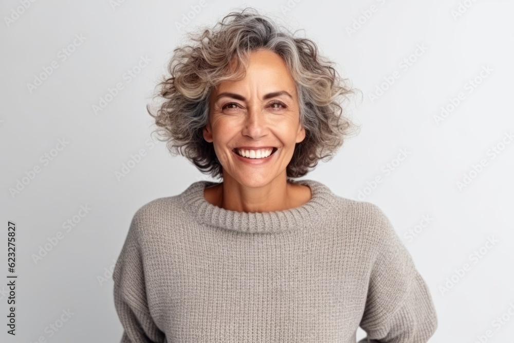 Portrait of a smiling middle-aged woman with gray hair in a gray sweater on a white background Portrait of a smiling middle-aged woman with gray hair in a gray sweater on a white background