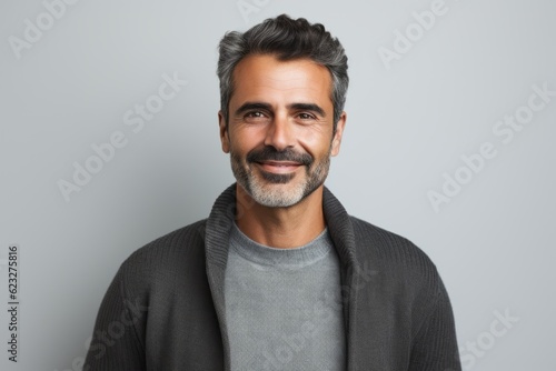 Handsome middle-aged man smiling at camera over grey background