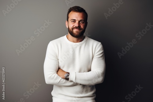 Portrait of a handsome bearded man in a white sweater on a gray background