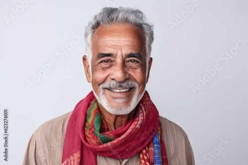 Portrait of a smiling Indian senior man with red scarf on white background