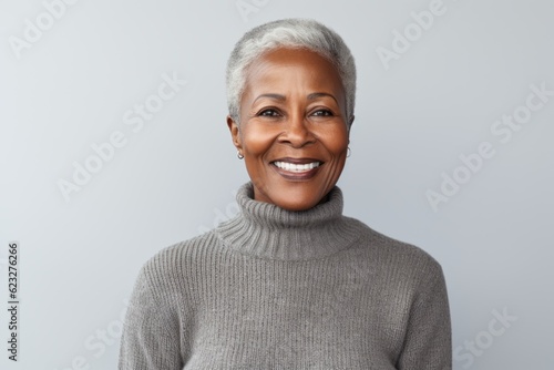 Close up portrait of smiling african american woman in grey sweater against white background